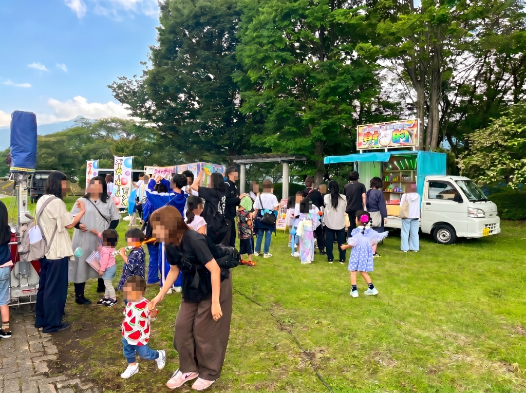 晴天の下、大勢の家族連れで賑わう出店風景